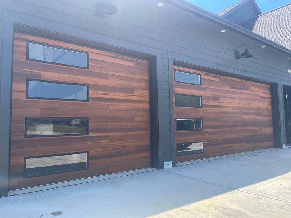 Modern wooden garage doors with large windows on a stylish home exterior.