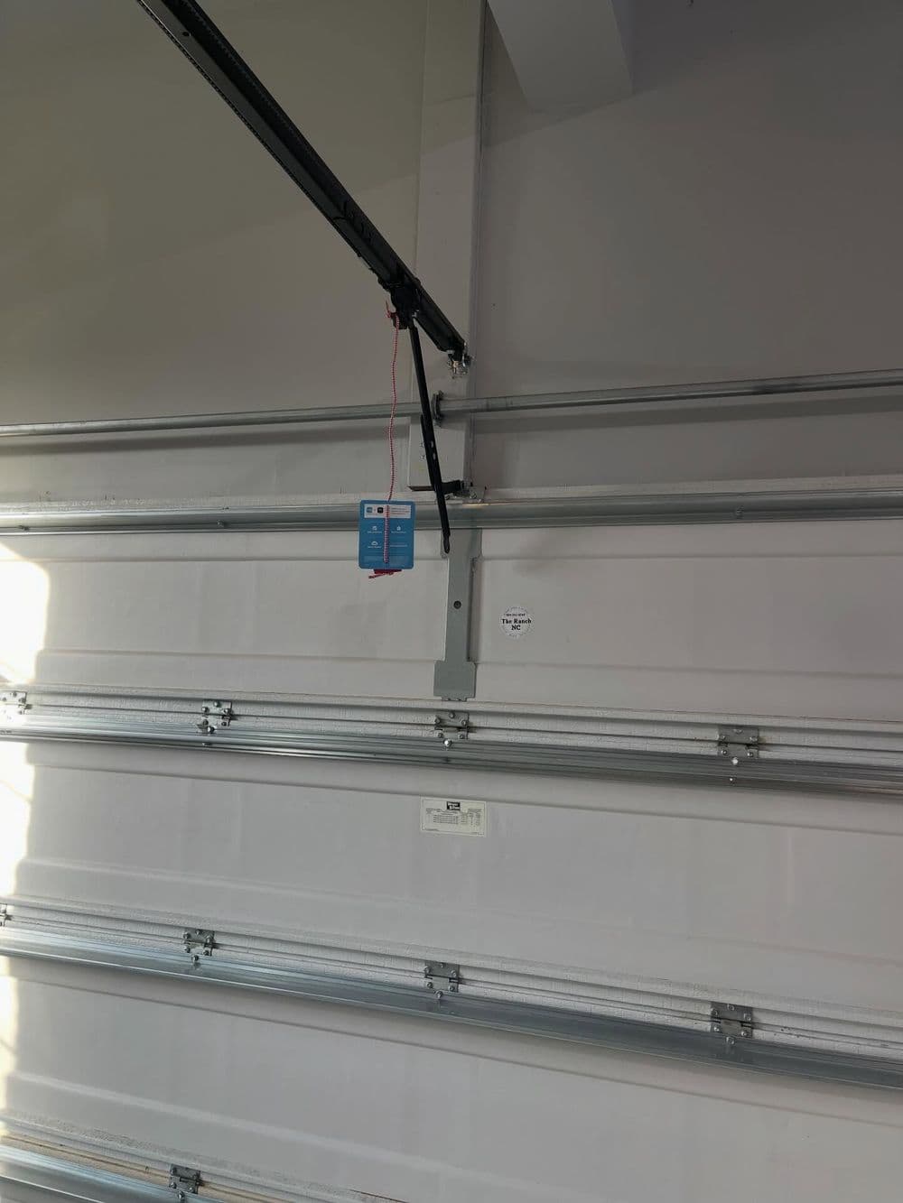Garage door opener installed on metal tracks in a garage interior.