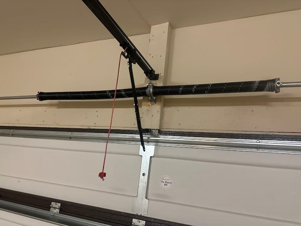 Garage door spring mechanism with pulley system and emergency release cord.