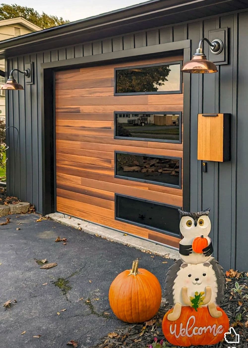 Modern garage door with wood accents, pumpkin, and Halloween decorations, including owl and hedgehog.